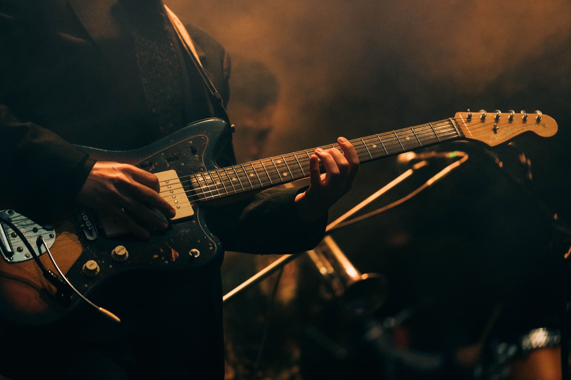 A guitarist performing live under warm stage lights